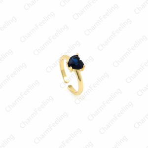 May include: A gold adjustable ring with a blue heart-shaped gemstone.