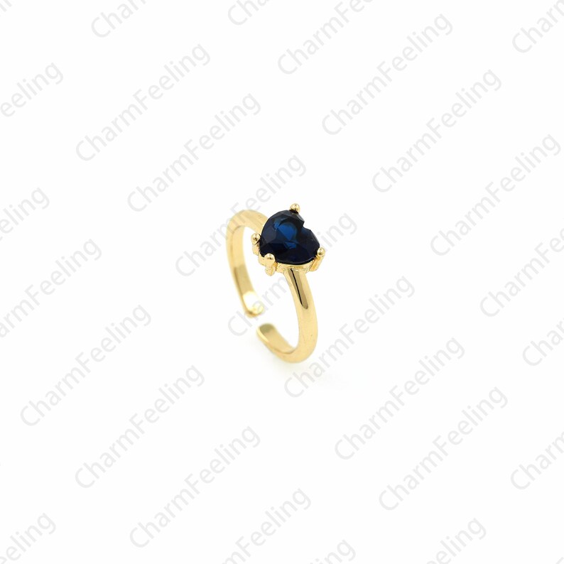 May include: A gold adjustable ring with a blue heart-shaped gemstone.