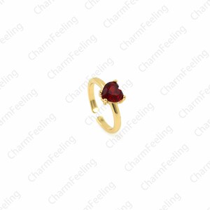May include: A gold adjustable ring with a red heart-shaped gemstone.