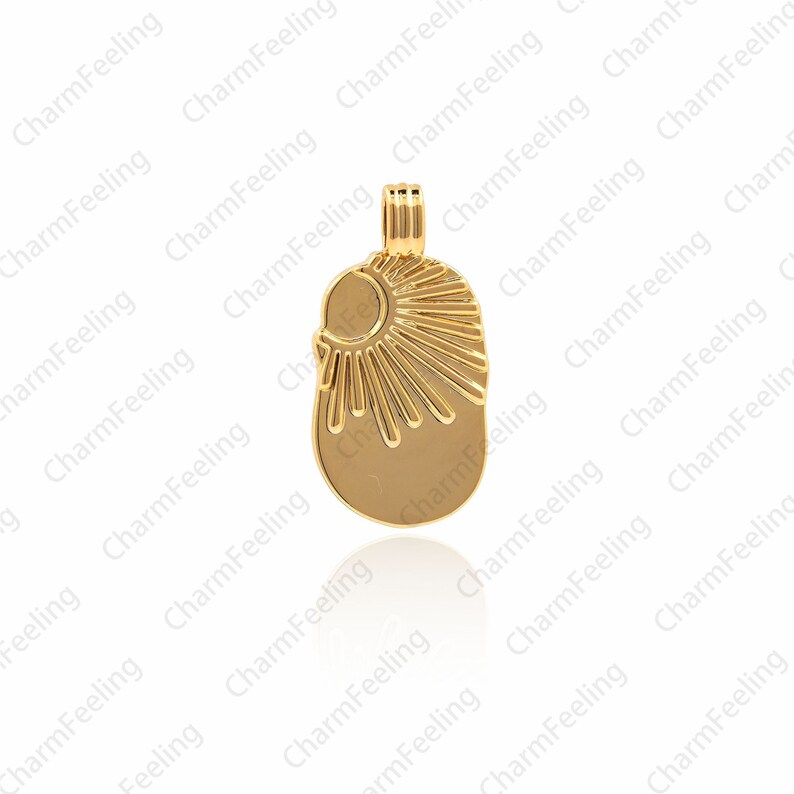 May include: A gold-toned pendant charm featuring a sunburst design with a crescent moon shape at the top. The charm is oval-shaped and has a smooth, polished finish.