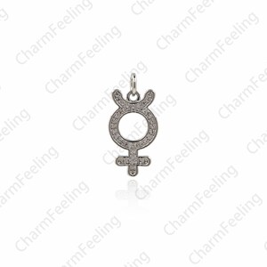 May include: A silver charm pendant in the shape of the astrological symbol for Venus, with a circle and a cross, covered in small clear cubic zirconia stones.
