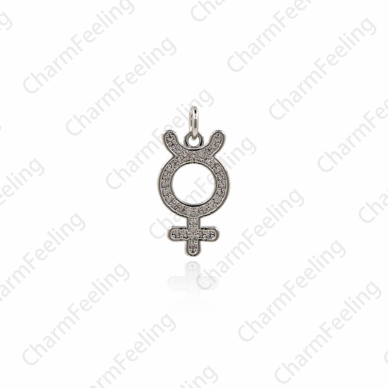 May include: A silver charm pendant in the shape of the astrological symbol for Venus, with a circle and a cross, covered in small clear cubic zirconia stones.