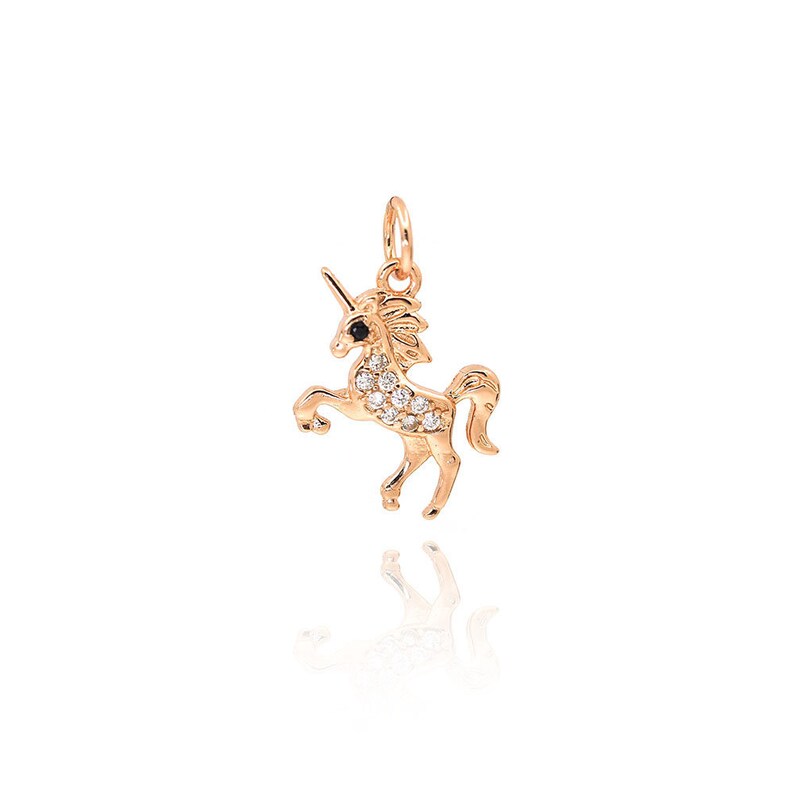 May include: A gold unicorn charm with a black eye and white cubic zirconia stones.