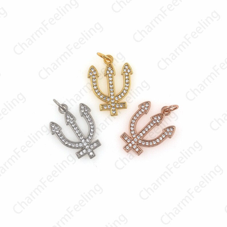 May include: Three trident charms with clear crystal accents. The charms are made of gold, silver, and rose gold metal.