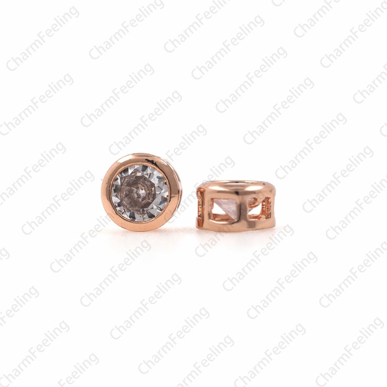 May include: Two gold-toned metal beads with a clear crystal stone on one bead and a geometric design on the other.