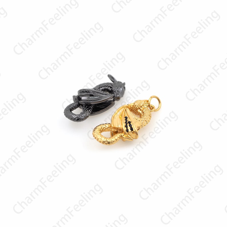 May include: Two dragon-shaped charms, one black and one gold, are shown on a white background. The charms are detailed and have a three-dimensional appearance.