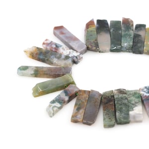 May include: A collection of green, brown, and gray agate gemstone slices, each with a unique pattern. The slices are arranged in a circle, with the points of the slices facing outwards.