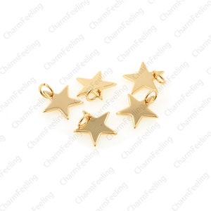 May include: Five gold-coloured star-shaped charms with jump rings. The charms are scattered on a white background.