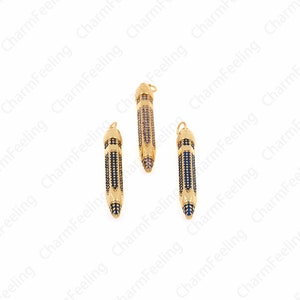 Pu&ograve; includere: Tre ciondoli a forma di matita dorati con strass blu e trasparenti. I ciondoli sono lunghi circa 5 cm.