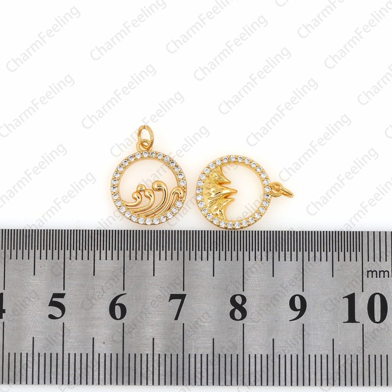 May include: Two gold-tone metal charms with clear rhinestone accents. The charm on the left features a wave design. The charm on the right features a mountain design. Both charms are approximately 2.5 cm in diameter.