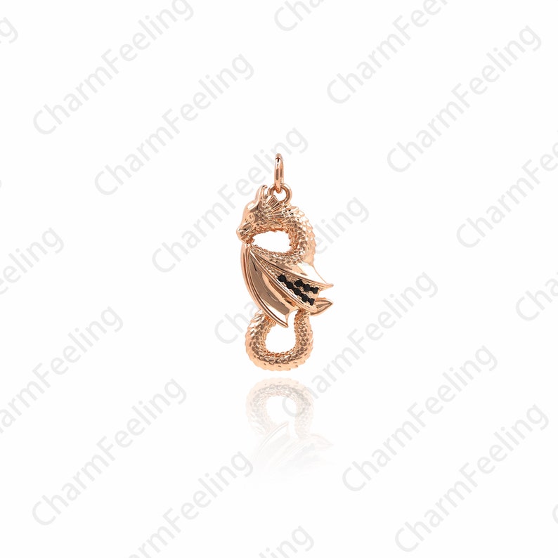 May include: A gold-toned dragon pendant with black accents. The dragon is curled up with its wings spread out. The pendant is on a white background.