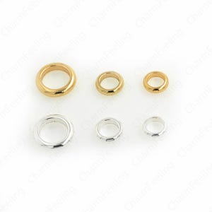 May include: A collection of six metal rings in varying sizes. Three are gold-toned, and three are silver-toned. The rings have a smooth, rounded design, suitable for jewelry making or crafting projects. The rings are displayed against a white background.