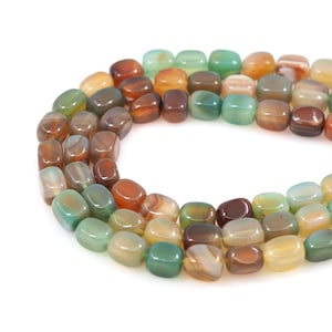 Peut inclure: Un brin de perles d'agate dans différentes nuances de vert, brun et orange. Les perles sont de forme ovale et ont une finition lisse et polie.