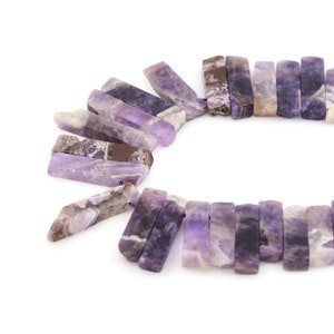 Peut inclure: Un brin de perles de pierres précieuses d'améthyste violette, chaque perle est de forme rectangulaire longue avec une finition brute et naturelle.