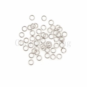 May include: A pile of silver jump rings, a type of jewelry finding used for connecting chains, cords, and other jewelry components.