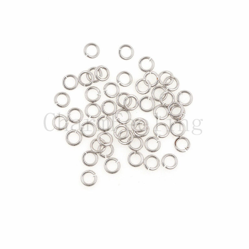 May include: A pile of silver jump rings, a type of jewelry finding used for connecting chains, cords, and other jewelry components.