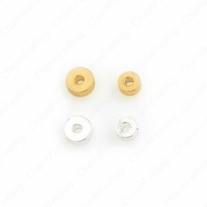 以下が含まれることがあります： 4つの小さな丸い金属ビーズ。2つは金色、2つは銀色です。各ビーズの中央には穴があります。ビーズは2つの異なるサイズで、2つの大きなビーズと2つの小さなビーズがあります。