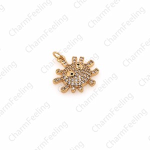 May include: Gold-tone charm featuring a sun with a face, accented with clear rhinestones. The charm has a loop for attaching to a bracelet or necklace.