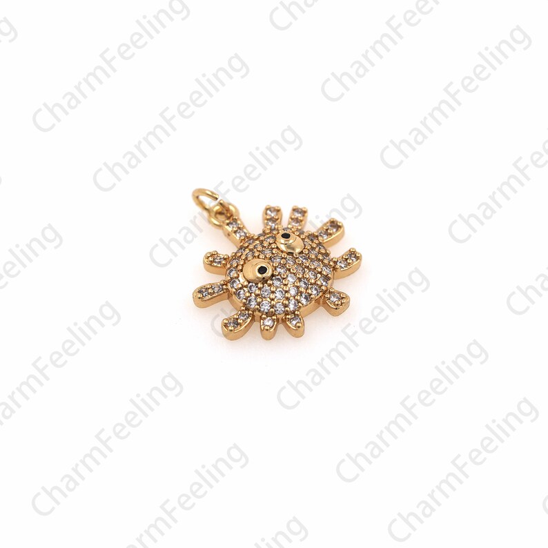 May include: Gold-tone charm featuring a sun with a face, accented with clear rhinestones. The charm has a loop for attaching to a bracelet or necklace.