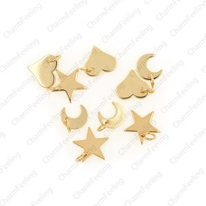 May include: A collection of gold-toned metal charms in the shapes of stars, hearts, and crescent moons. Each charm has a jump ring for attaching to a bracelet or necklace.