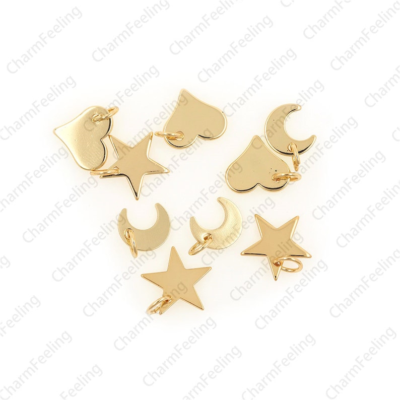 May include: A collection of gold-toned metal charms in the shapes of stars, hearts, and crescent moons. Each charm has a jump ring for attaching to a bracelet or necklace.