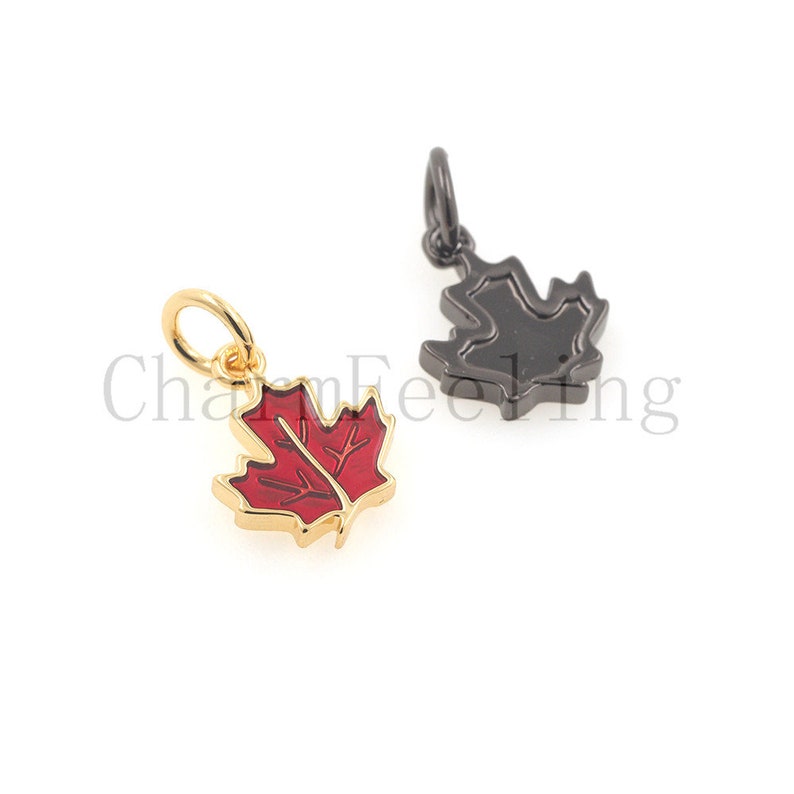 May include: Two maple leaf charms, one gold with red enamel and one black metal.