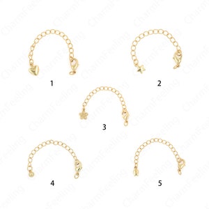 Peut inclure: Cinq chaînes d'extension de collier dorées. Chaque chaîne a un charme différent : un cœur, une étoile, une fleur, une petite boule et une goutte. Chaque chaîne est dotée d'un fermoir mousqueton pour une fixation facile.