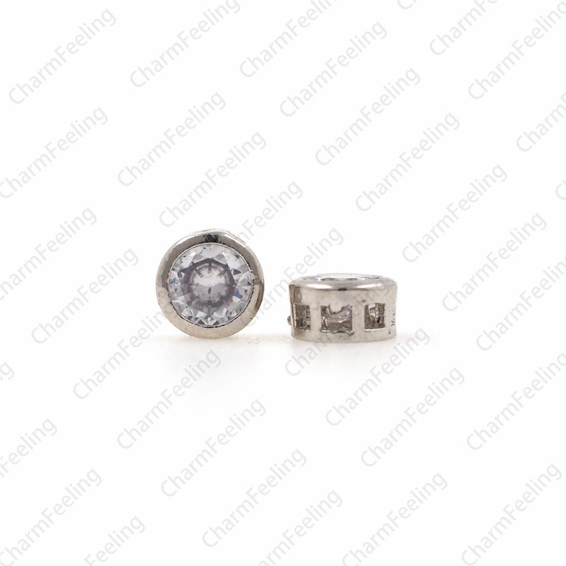 May include: Two silver earring studs with clear cubic zirconia stones. One stud has a round stone and the other has a square stone.