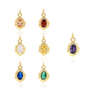 Puede incluir: Conjunto de 8 colgantes de tono dorado con piedras preciosas ovaladas en varios colores, incluyendo rojo, naranja, amarillo, verde, azul, morado y blanco. Cada colgante presenta una forma texturizada irregular.