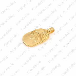 May include: A gold-colored pendant charm in the shape of a sun with rays emanating from the center. The pendant has a loop at the top for attaching to a chain or bracelet.