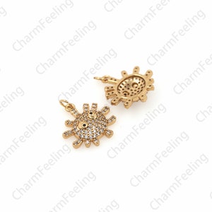 May include: Two gold-tone metal charms in the shape of a sun with a face. The charms are covered in clear rhinestones and have black accents for the eyes.