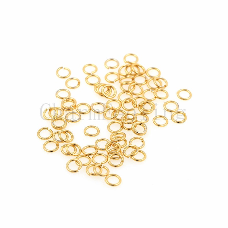 May include: A pile of gold jump rings, a type of jewelry finding used for connecting chains, cords, and other jewelry components.