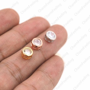 May include: Three round, clear crystal charms with a metal setting. The charms are in gold, rose gold, and silver.