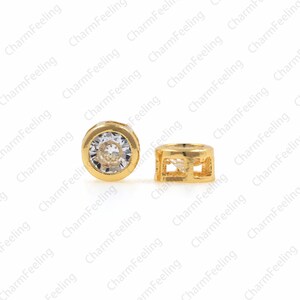 May include: Two gold-toned metal bead caps with clear rhinestones. One cap has a round shape with a clear rhinestone in the center. The other cap has a square shape with an open design.
