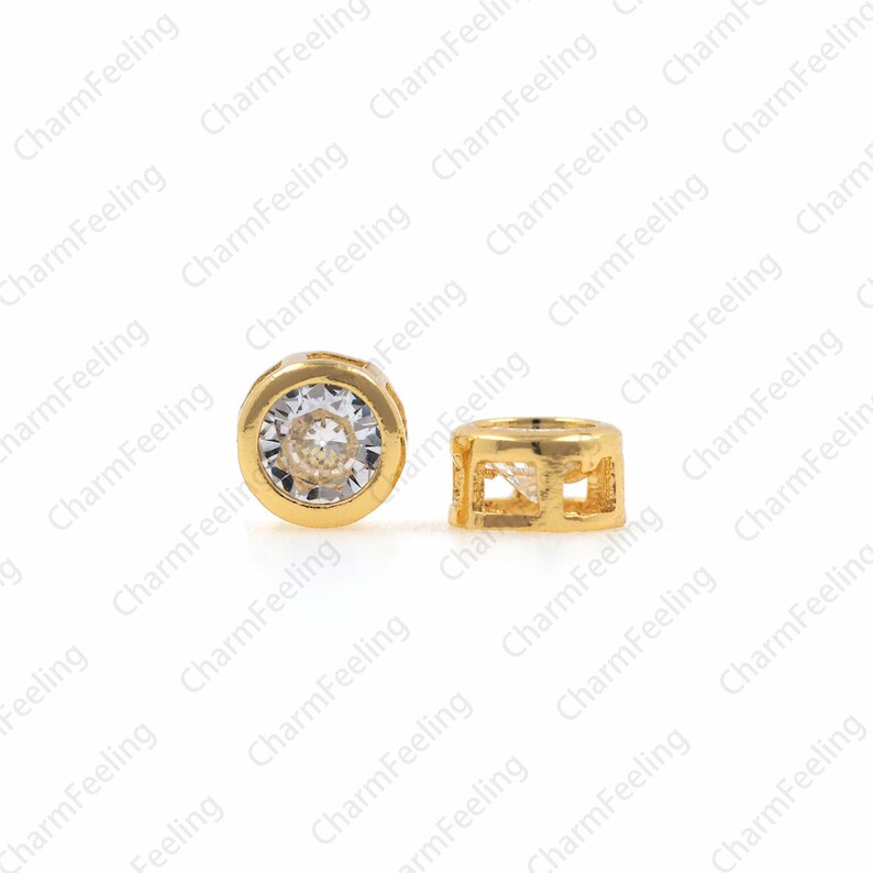 May include: Two gold-toned metal bead caps with clear rhinestones. One cap has a round shape with a clear rhinestone in the center. The other cap has a square shape with an open design.