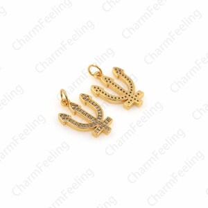 May include: Two gold-tone trident charms with clear crystal accents. The tridents are detailed with a textured surface.