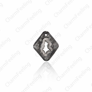 Puede incluir: Un colgante de forma de diamante plateado con un dise&ntilde;o claro, texturizado y cristalino. El colgante tiene un agujero en la parte superior para sujetarlo a una cadena o cord&oacute;n.