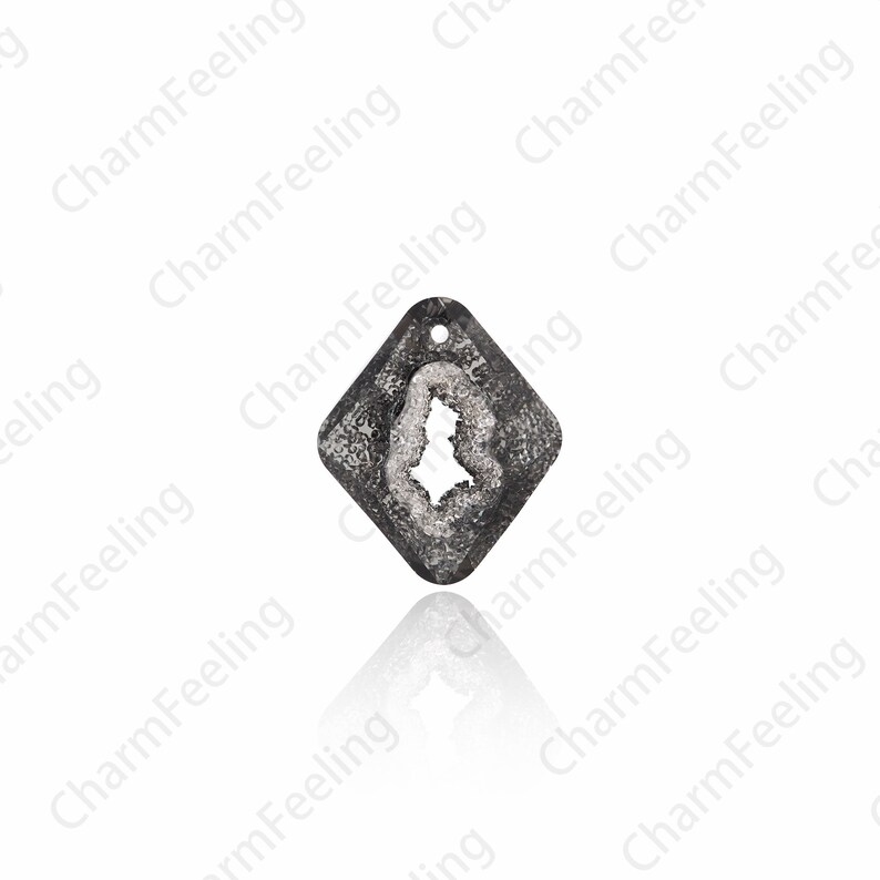 Puede incluir: Un colgante de forma de diamante plateado con un dise&ntilde;o claro, texturizado y cristalino. El colgante tiene un agujero en la parte superior para sujetarlo a una cadena o cord&oacute;n.