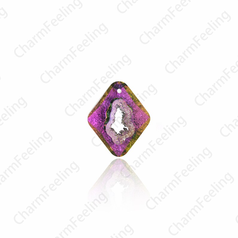 Puede incluir: Un colgante de forma de diamante morado y dorado con una piedra de &aacute;gata clara en el centro. La piedra tiene una textura natural, rugosa y una apariencia blanca y nublada.