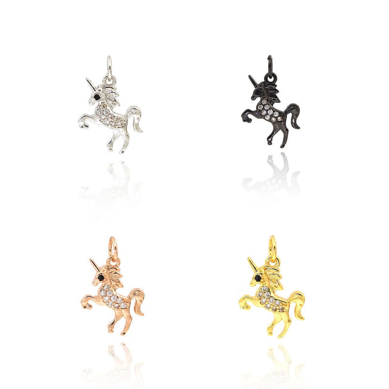 May include: Four unicorn charms in different colors: silver, black, rose gold, and gold. Each charm is adorned with sparkling clear rhinestones.