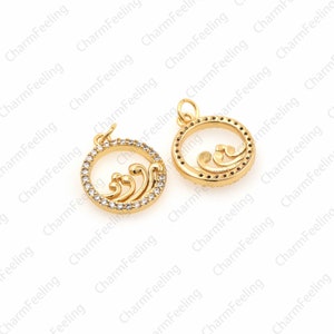 May include: Two gold-tone metal charms featuring a wave design and clear rhinestones. The charms are circular and have a loop at the top for attaching to a necklace or bracelet.