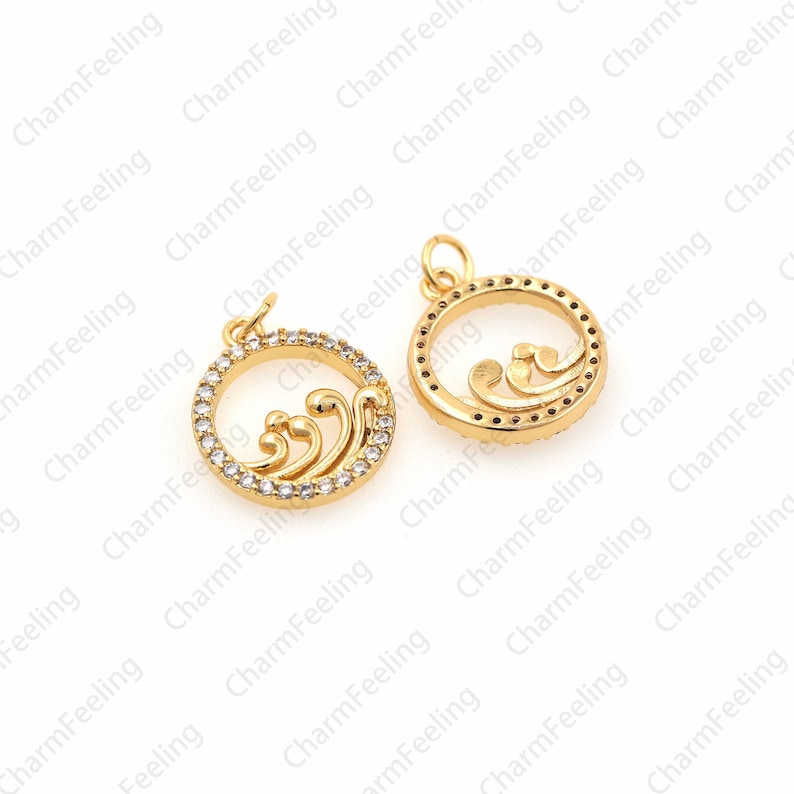May include: Two gold-tone metal charms featuring a wave design and clear rhinestones. The charms are circular and have a loop at the top for attaching to a necklace or bracelet.