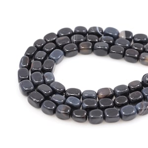 May include: A strand of black agate gemstone beads, each bead is a smooth, rectangular shape with a slightly rounded edge. The beads are arranged in a circular pattern.