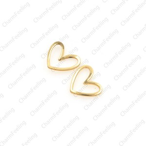 May include: Two gold-colored metal heart-shaped charms with an open center.