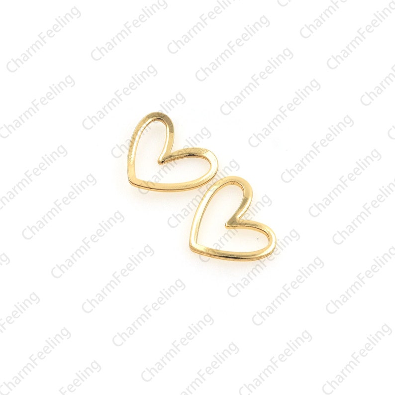 May include: Two gold-colored metal heart-shaped charms with an open center.
