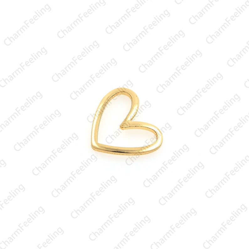 May include: A gold-colored metal heart charm with an open center. The heart is a simple design with a smooth finish.
