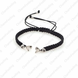 Puede incluir: Un brazalete trenzado negro con cierres de metal plateado en forma de coraz&oacute;n. El brazalete tiene un nudo deslizante para ajustar el tama&ntilde;o.