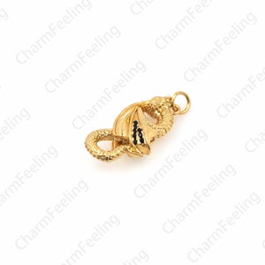 May include: Gold-toned dragon charm with black accents. The dragon is curled up with its tail in its mouth.