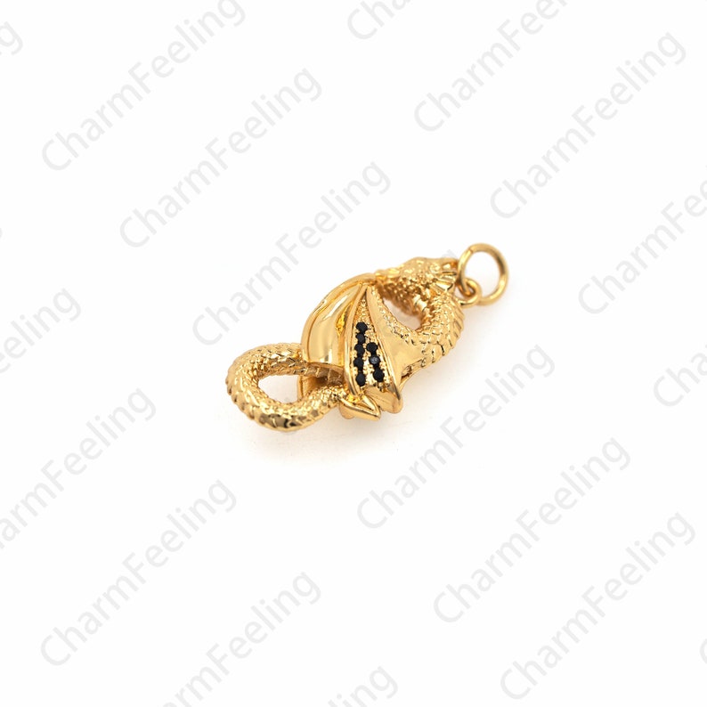 May include: Gold-toned dragon charm with black accents. The dragon is curled up with its tail in its mouth.