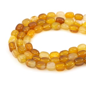 Puede incluir: Un hilo de cuentas de piedras preciosas pulidas y pulidas en tonos amarillos y marrones. Las cuentas tienen una forma rectangular redondeada y un acabado liso y brillante. Las cuentas están ensartadas, creando un collar o una pulsera.